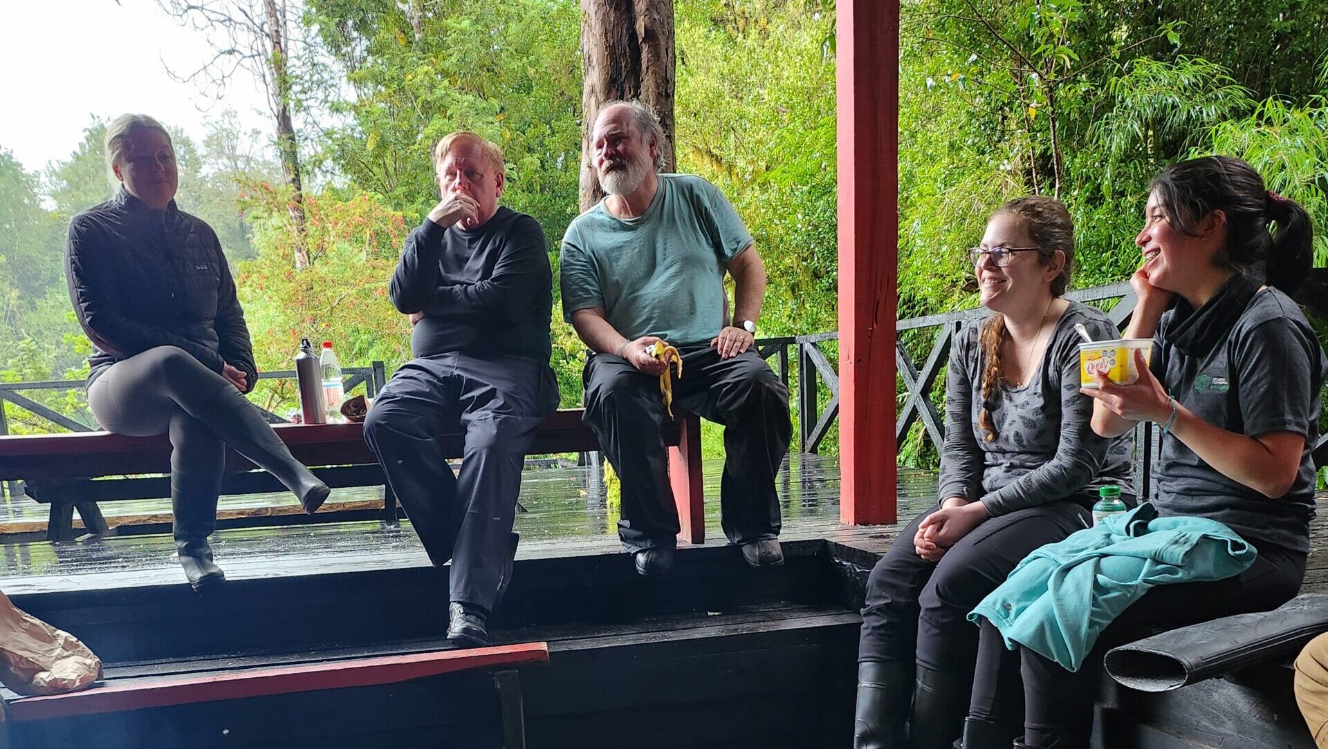 Five nature guardians smile while sitting around a fire.